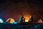 Couple holding hands by campfire while camping at night at Lost Coast Trail, California, USA