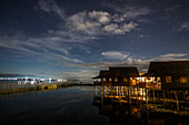 Sky and clouds over illuminated Inle Lake stilt houses at night, Shan State, Myanmar