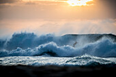 Surfer riding wave at sunset, Oahu, Hawaii, USA