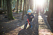 Baby boy riding children's bike in forest, Harrison Hot Springs, British Columbia, Canada