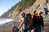 Female backpackers smiling while hiking along beach, Lost Coast Trail, Kings Range National Conservation Area, California, USA