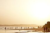 Sunset on the beach of the Three Brothers (Praia dos Tr??????s Irm??????os in portuguese) . you can see the silhouettes of multidud of people enjoying the last rays of sun.