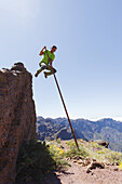 man jumping with the canarian crook, Salto del Pastor Canario, Pared de Roberto, basaltic rock, crater rim, Caldera de Taburiente, UNESCO Biosphere Reserve, La Palma, Canary Islands, Spain, Europe