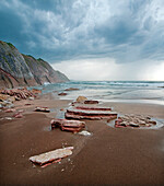 Storm clouds over rocks on beach, Zumaia Beach, Basque Coast Geopark, Spain