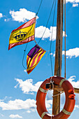 Spanische Flaggen an einem Fischerboot mit Rettungsring im Hafen,  Port d'Alcudia, Mallorca, Spanien
