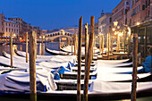 Rialto Bridge with snow-covered gondolas at dusk after a snowfall, Grand Canal, Venice, Veneto, Italy
