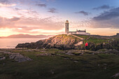 Fanad Head (Fánaid) lighthouse, County Donegal, Ulster region, Ireland, Europe. A photographer on the field at sunrise near Fanad Head lighthouse