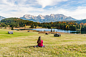 Woman sitting and staring at Gerold lake and Karwendel Alps. Krün, Upper Bavaria, Bavaria, Germany.
