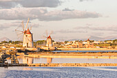 Salt pans with rows of tanks and two fully functional windmills on the coast connecting Marsala to Trapani, Trapani province,Sicily,Italy