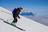 Woman backcountry skiing descending from Hinteres Sonnwendjoch, Kaiser range in background, Hinteres Sonnwendjoch, Bavarian Alps, Tirol, Austria