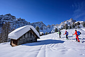 Three persons backcountry skiing ascending to Medalges, Geisler range in background, Medalges, Natural Park Puez-Geisler, UNESCO world heritage site Dolomites, Dolomites, South Tyrol, Italy