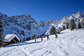 Several persons backcountry skiing ascending to Medalges, Geisler range in background, Medalges, Natural Park Puez-Geisler, UNESCO world heritage site Dolomites, Dolomites, South Tyrol, Italy