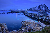 Lighthouse of Gimsoy at dusk with snow-covered mountains in background, Lofoten, Nordland, Norway