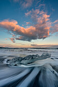 Block of ice on the black beach at sunset in Jokulsarlon Glacier Lagoon, Austurland, Eastern Iceland, Iceland, Europe