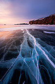 A flat ice with cracks of the lake Baikal at sunrise, Irkutsk region, Siberia, Russia