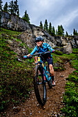 Portrait of Woman mountain biker rides downhill in scenic landscape on the Ice Lakes trail, USA