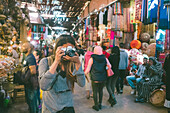 Female tourist taking photo in Jemaa el-Fnaa souk, Marrakesh, Morocco