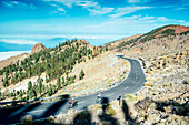 Two cyclists pedaling on mountain road, Teide National Park, Tenerife, Canary Islands, Spain
