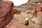 Woman camping with tent in The Grabens near Colorado River in Canyonlands National Park, Moab, Utah, USA