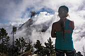 Rear view shot of young female hiker looking at view of Fuego Volcano, Guatemala