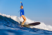 Full length shot of woman with arm raised surfing in sea