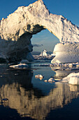 Dramatic arch formed in an iceberg that came from the Ilulissat Icefjord. Climate change is amplifying the speed in which the glaciers of Greenland are calving icebergs, which can be found around Ilulissat in abundance.