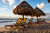 Recliners covered with awnings on beach at sunrise, Puerto Morelos, Yucatan Peninsula, Mexico