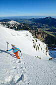 Frau auf Skitour steigt zu Fuß über steilen Hang auf, Hochmiesing, Spitzing, Bayerische Alpen, Oberbayern, Bayern, Deutschland