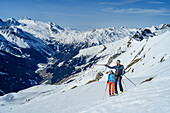 Man and woman backcountry-skiing looking towards Zillertal Alps, Rastkogel, Tuxer Alps, Tyrol, Austria