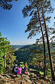 Three persons sitting at vista-point and looking towards valley of Alb, Dachsberg, Albsteig, Black Forest, Baden-Wuerttemberg, Germany