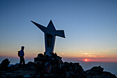 Frau beim Bergsteigen steht bei Sonnenaufgang am Gipfel des Viso Mozzo, Viso Mozzo, Giro di Monviso, Monte Viso, Monviso, Cottische Alpen, Piemont, Italien