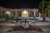 Frau in Karawanserei auf Perserteppichen, Iran, Asien