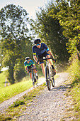 two young men on gravel bikel on a gravel road, Muensing, bavaria, germany