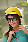 Young  woman with bike helmet in front of a modern facade, Munich, bavaria, germany