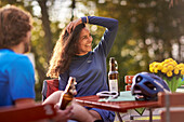 Young  woman and young man on bicycletour sitting in beergarden, Muensing, Lake Starnberg;  bavaria, germany