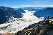 Woman hiking looking at mood of fog above lake Achensee, Rofan and Karwendel in background, Seebergspitze, Karwendel range, Tyrol, Austria