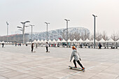 chinese youth with Longboards in front of so called Bird’s Nest of Herzog & de Meuron, National Stadium, heavy air pollution, Olympic Green, Beijing, China, Asia