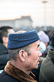 Mann mit komischer Kopfbedeckung beobachtet Flaggen Zeremonie und Wachablösung am Platz des Himmlischen Friedens, Peking, China, Asien