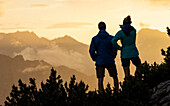Young woman and man look watch the sunset mountain scenerie, silhouette, Scharnitz, Tirol, Österreich