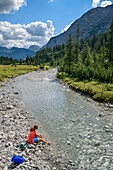 Frau beim Wandern badet Füße im Lech, Lechweg, Lechquellengebirge, Vorarlberg, Österreich