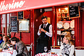 Waiter talking to a tourist at the La Mère Catherine restaurant, Place du Tertre, Montmartre, Paris, France, Europe