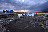 Eine Gruppe Fotografen, versammelt am Wasserfall Godafoss, fängt die Abendstimmung ein, Island, Europa