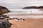 Eine Frau badet im Meer an der Sandwood Bay, Highlands, Schottland, Großbritannien