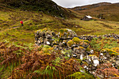 A hiker on arrival at Suileag Bothy, Inverpolly Nature Reserve, Highlands, Scotland, UK