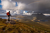 Wanderer blickt vom Stac Pollaidh auf Loch Sionasgaig und Cul Mor, Inverpolly Nature Reserve, Highlands, Schottland, Großbritannien