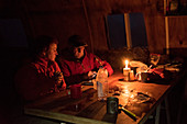A couple at the table inside the Refugio Garcia Soto (Chile) by candlelight, Los Glaciares National Park, Patagonia, Argentina