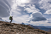 Climber looks into the valley at the Paso del Viento, cloud swirls in the sky, Los Glaciares National Park, Patagonia, Argentina