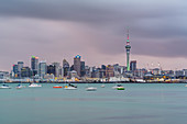 Skyline of Auckland CBD under a gloomy sky at dusk. Auckland City, Auckland region, North Island, New Zealand.