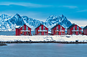 Dusk on red cabins (Rorbu) overlooking the icy sea, Svolvaer, Lofoten Islands, Norway