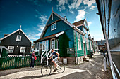 Fahrradfahrer und typische Häuser in Kerkbuurt, Insel Marken, Nordholland, Niederlande